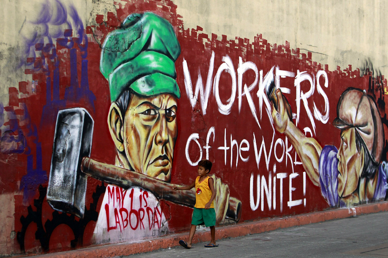 Un niño camina frente a un grafiti sobre el día internacional del trabajador con el lema &#8220;Trabajadores del Mundo, ¡Uníos!&#8221; en Manila. Se espera que miles de filipinos participen en las protestas del 1 de mayo para exigir mejores condiciones laborales para los trabajadores con salarios bajos. EFE/Ritchie B. Tongo