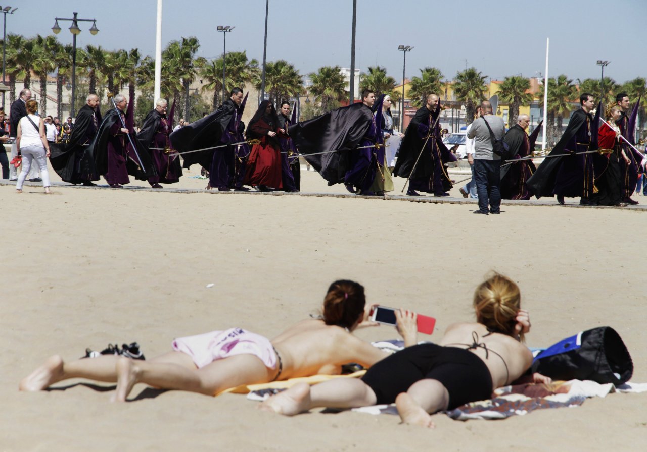 
Penitentes junto a los bañistas en una playa de Valencia durante una procesión para orar por aquellos que murieron en el mar. Cientos de ritos y precesiones se desarrollan durante la Semana Santa que culmina el domingo de Pascua de Resurrección. (REUTERS )