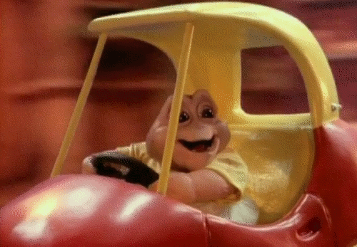 Baby Sinclair from Dinosaurs riding in his red and yellow kiddie car